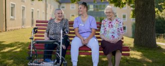 Theresianum Drei gemeinsam lachende Personen auf einer Parkbank.